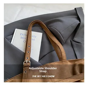 Détail de la bandoulière réglable avec boucle argentée sur le sac cabas en daim marron