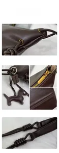 Close-up of vintage brown leather bag with golden hardware, stitching, and charms