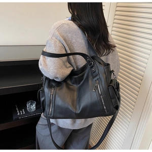 Detail view of large black pebble leather tote bag worn as a shoulder bag on a model