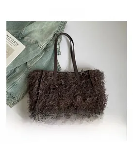 Détail d'un sac à franges marron avec lanières en cuir et boucles sur du denim