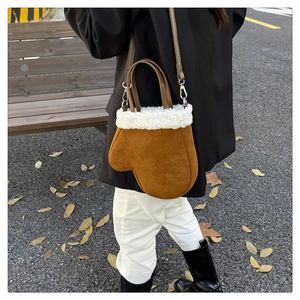 Outdoor view of a brown suede glove-shaped crossbody bag with white faux fur trim detail