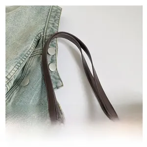 Détail de la poignée en similicuir marron et des franges en peluche d'un sac cabas
