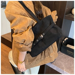 Détail du sac à bandoulière en daim noir avec boucle argentée et design rétro minimaliste