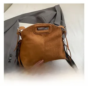 Close-up of brown suede bag featuring dense long tassels and integrated handle design