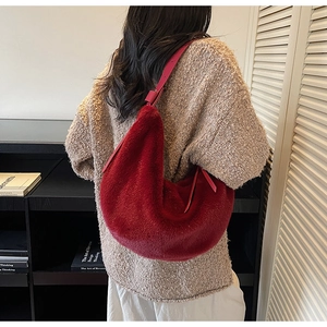 Sac hobo en peluche rouge foncé porté épaule, montrant la texture douce de fausse fourrure