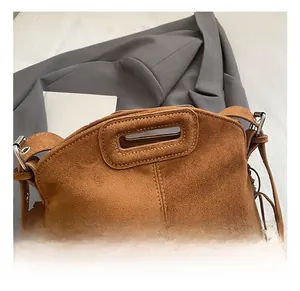 Detail of brown suede tote bag with integrated handle and stylish side fringe accents