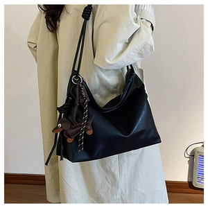 Detail of black large Hobo shoulder bag with knot strap and brown dachshund pendant