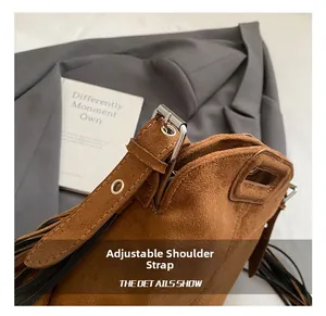 Detail of adjustable metal buckle strap and side tassel on brown faux suede handbag