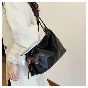 Detail of black faux leather tote with brown puppy charm for daily commute and fashion