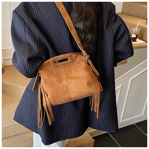 Detail of vintage brown suede crossbody bag with long side tassels and adjustable strap