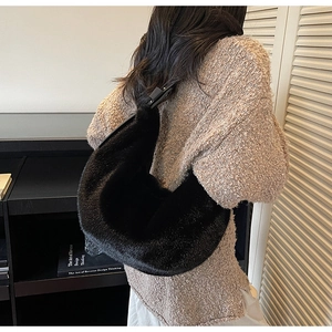 Gros plan du sac hobo en fausse fourrure noire porté avec un pull en maille beige