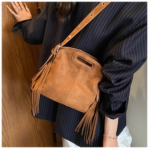 Detail shot of brown frosted suede crossbody bag with long side tassels and eyelet strap