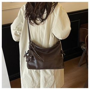 Detail of dark brown leather tote bag with woven chain strap and horse charm