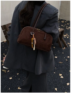 Dettaglio borsa boston in camoscio marrone scuro con ciondolo di perline su blazer