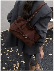 Détail du sac cabas en daim marron foncé avec boucles métalliques argentées en décor automnal