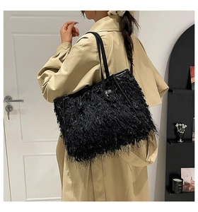 Détail d'un sac cabas noir en plumes porté avec un trench beige pour un style élégant