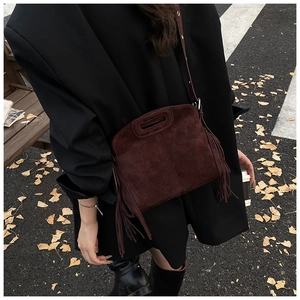 Detail view of burgundy faux suede crossbody bag with boho fringe and adjustable strap