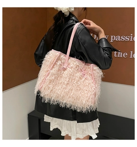 Sac fourre-tout rose à longues franges porté par un mannequin dans une tenue en cuir élégante