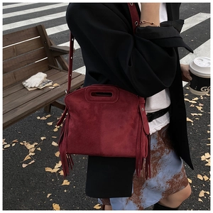 Detail of dark red suede crossbody bag with elegant long tassels and top handle hole