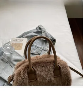 Detail of plush brown tote bag with leather handles and metallic zipper on a casual setup