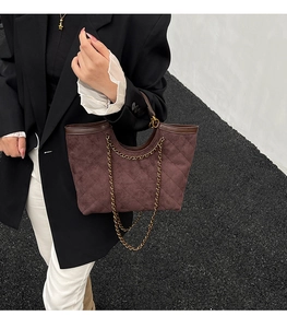 Detail view of burgundy quilted tote bag with chunky gold chain handles and matte leather