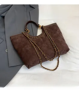 Detail of dark brown quilted tote bag with chain strap and soft matte suede texture