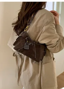 Detail of dark brown suede tote bag featuring decorative buckles and vintage gold hardware