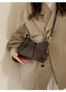 Detail of dark brown suede shoulder bag with contrast stitching and side pockets