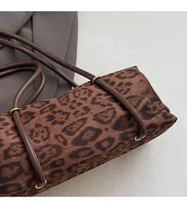 Detailed macro view of leopard print shoulder bag with gold metal rings and soft suede fabric
