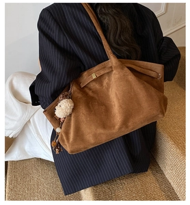 Detailansicht der braunen Wildledertasche mit Plüschwelpen-Anhänger und Metallschnalle