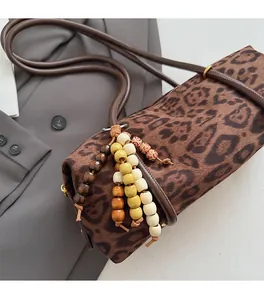 Detail of leopard print cylinder bag with colorful wooden bead charm and gold hardware