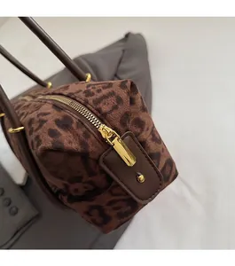 Close-up of smooth gold metal zipper and leather pull on leopard print suede handbag
