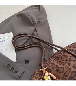Detail of leopard print tote bag with beaded tassel charm and comfortable brown strap