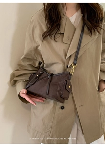 Detail of dark brown retro crossbody bag with matte finish and gold hardware