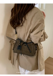 Detail of dark brown suede shoulder bag with black leather trim and white stitching