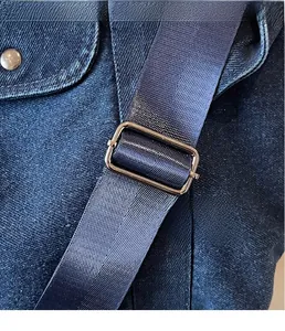 Detail of blue nylon strap with silver metal buckle on a casual denim tote bag