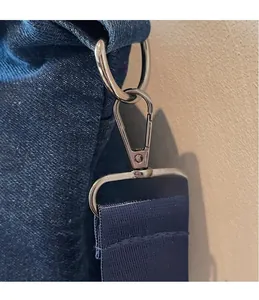 Close-up of the silver metal hook and durable nylon shoulder strap on the denim tote bag