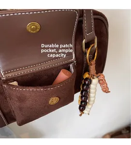 Detail of vintage brown bag with functional front pocket and decorative beaded charm