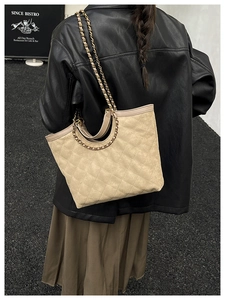 Beige quilted chain tote bag styled with a leather jacket in an urban street setting