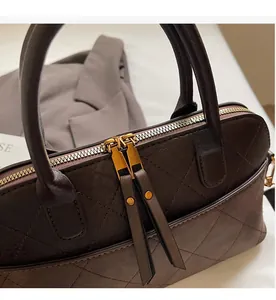 Close-up of smooth double zipper and vintage rhombic quilted leather on the coffee brown bag