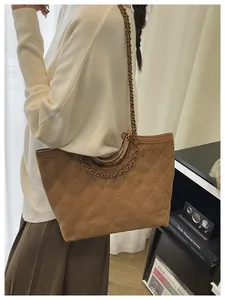Close-up of brown quilted tote bag showing suede texture and metal chain strap detail