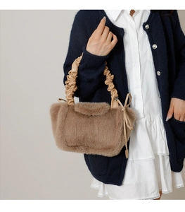 Detail of plush faux fur shoulder bag with ruched leather handle and bow decoration
