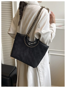 Dettaglio della borsa shopper trapuntata nera con catena d'oro vintage e camoscio