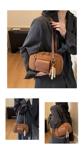 Detail of retro brown suede Boston bag featuring leather pockets and wooden bead charm