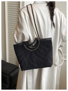 Close-up of black quilted tote bag featuring a textured finish and metal chain straps