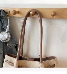 Close-up of beige suede tote bag with brown leather trim and silver hardware detail