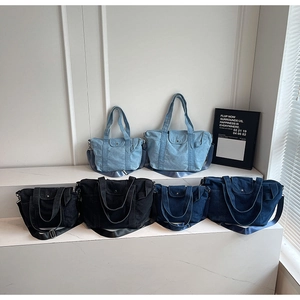 Multiple sizes of denim tote bags in light blue, dark blue, and black on display