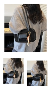 Detail of black suede shoulder bag with contrast stitching and decorative wooden beads