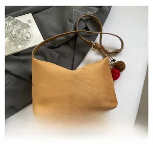 Nahaufnahme der Retro-Wildleder-Tasche mit Plüschkugel-Anhänger und Metallringen