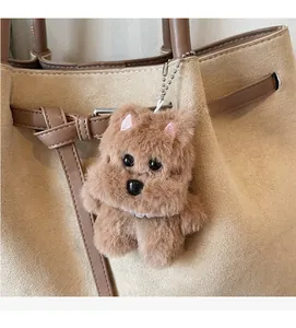 Brown fluffy dog plush bag charm with pearl necklace and bone tag on a tote bag